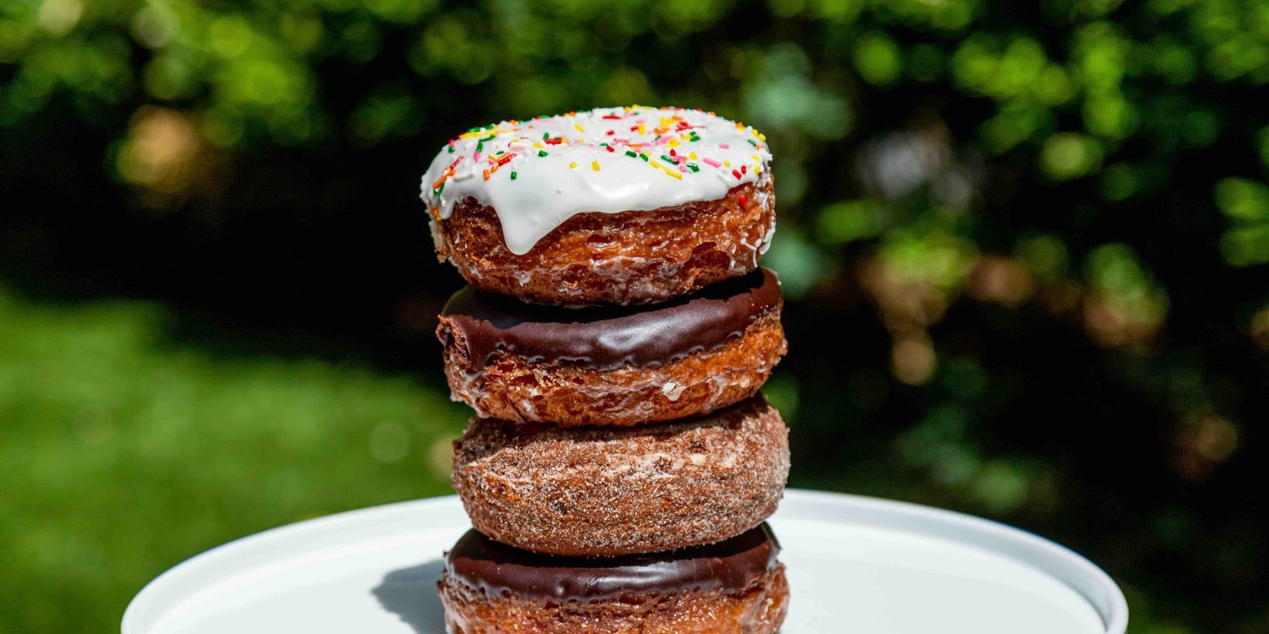 Four donuts stacked on top of each other on a platter.